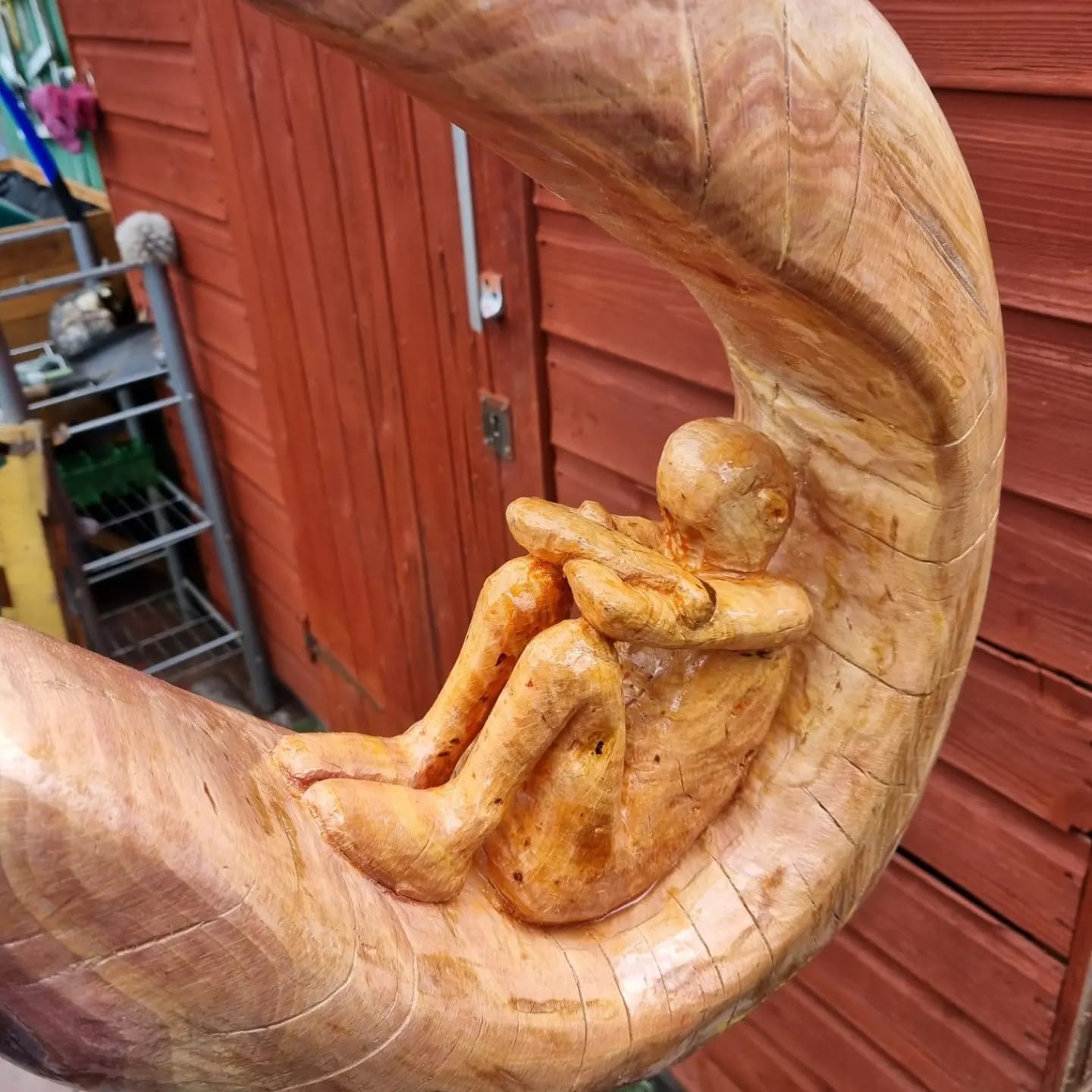 Wood carving — figure sitting in crescent moon, chain grown into tree trunk